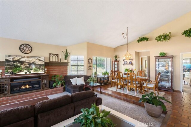 tiled living room featuring vaulted ceiling, a brick fireplace, and a chandelier