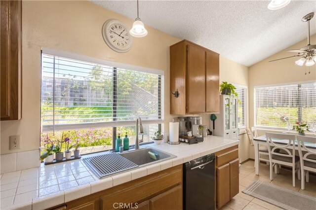 kitchen with a sink, vaulted ceiling, black dishwasher, and a textured ceiling