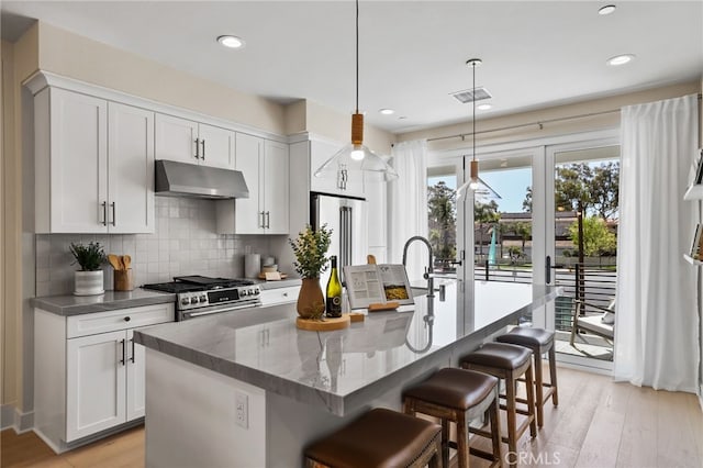 19011 Main St Unit 121, Huntington Beach, CA 92648 - kitchen with an island with sink, visible vents, under cabinet range hood, stainless steel appliances, and backsplash