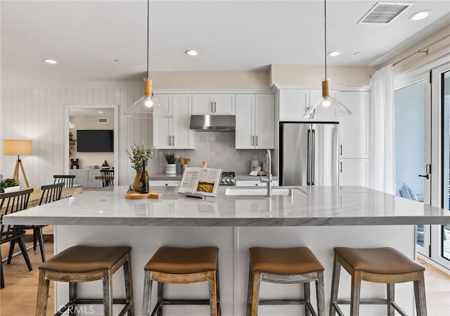 19011 Main St Unit 121, Huntington Beach, CA 92648 - kitchen featuring visible vents, a sink, under cabinet range hood, high end fridge, and decorative backsplash