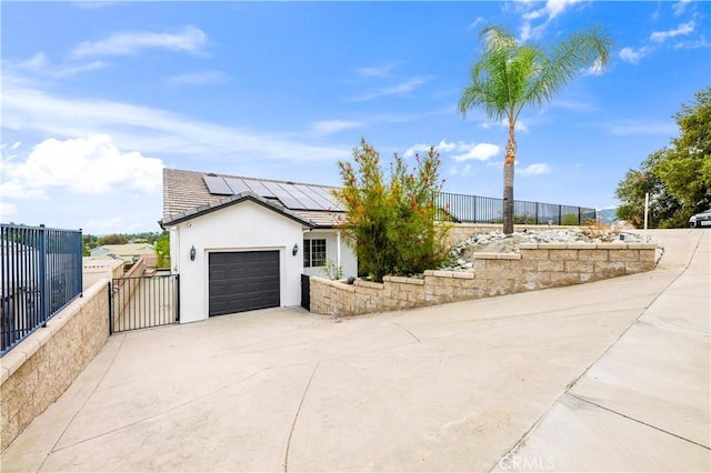 view of front of property with roof mounted solar panels, concrete driveway, fence, and an attached garage