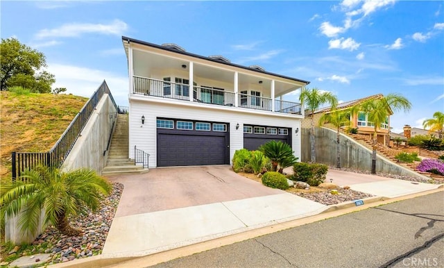 view of front facade featuring driveway, stairway, fence, a balcony, and a garage