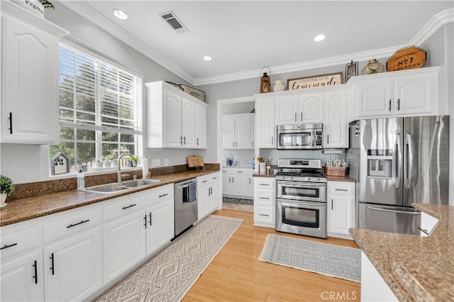 kitchen featuring crown molding, a sink, stainless steel appliances, visible vents, and white cabinets