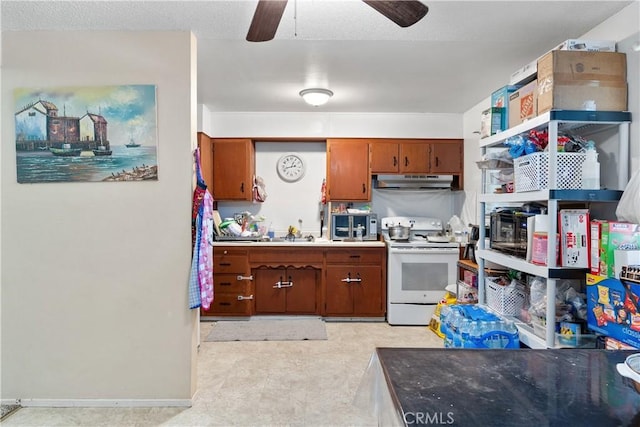 kitchen with a ceiling fan, brown cabinetry, baseboards, under cabinet range hood, and white electric range