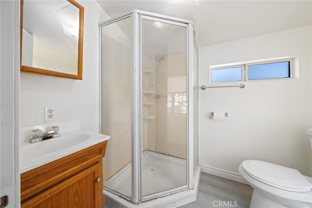 full bathroom featuring wood finished floors, toilet, a stall shower, and vanity