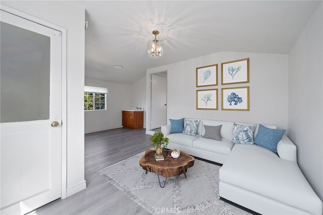 living room featuring baseboards, an inviting chandelier, wood finished floors, and vaulted ceiling