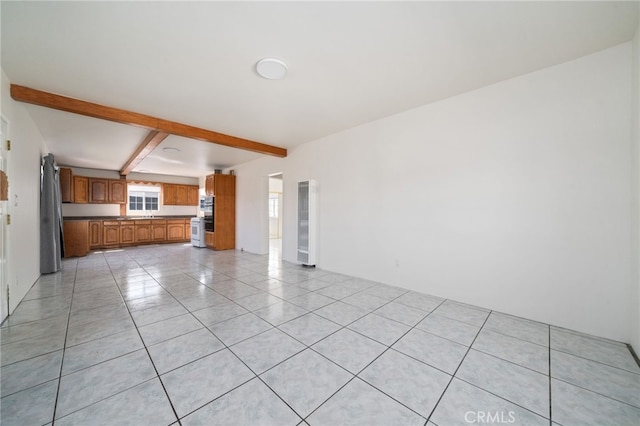 unfurnished living room featuring beam ceiling and light tile patterned floors
