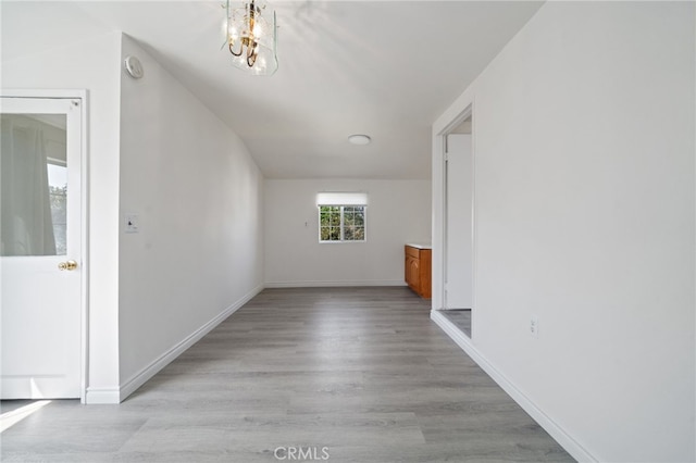 interior space featuring baseboards, an inviting chandelier, and light wood finished floors