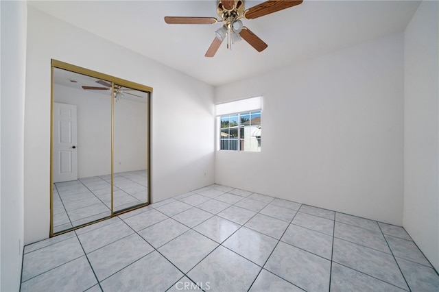 unfurnished bedroom with light tile patterned floors, a ceiling fan, and a closet