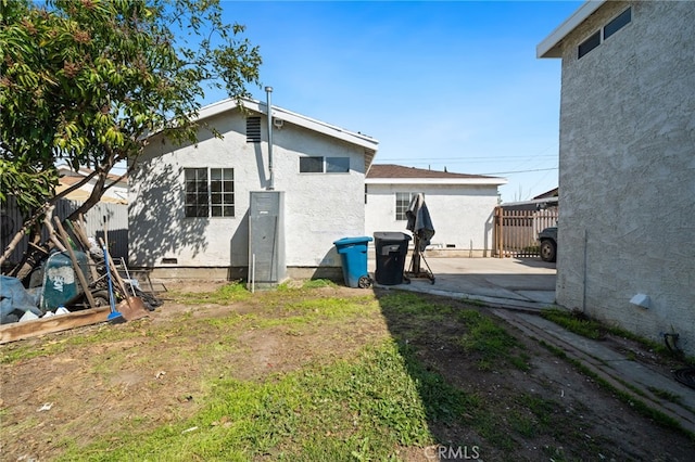 rear view of property with crawl space, stucco siding, fence, and a patio area