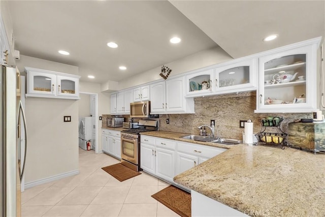 kitchen with white cabinets, light stone counters, a sink, appliances with stainless steel finishes, and backsplash