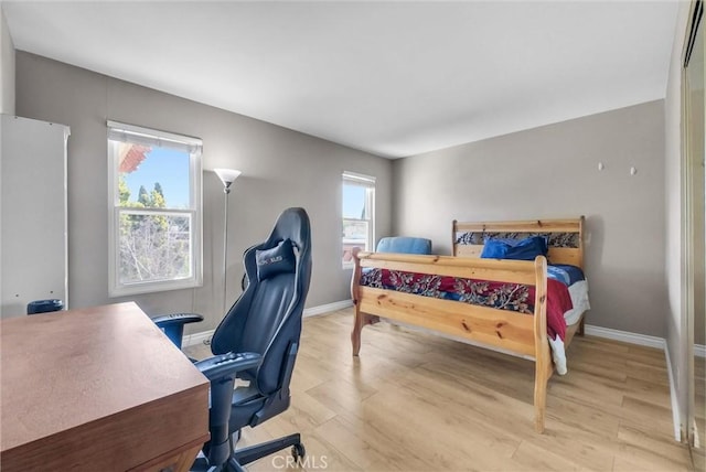 bedroom featuring baseboards, multiple windows, and wood finished floors