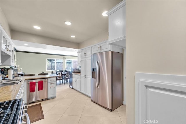 kitchen with light tile patterned floors, appliances with stainless steel finishes, a sink, and a peninsula
