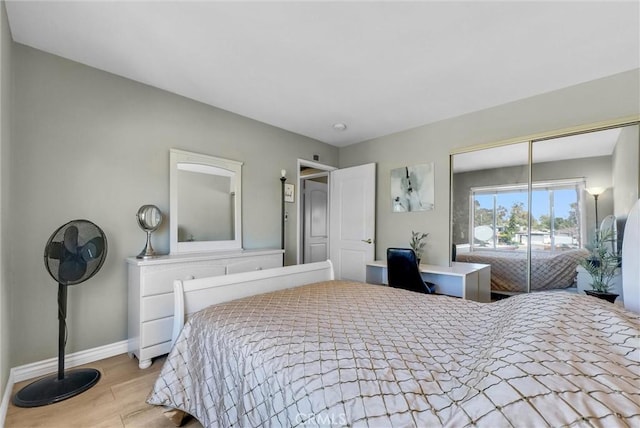 bedroom featuring baseboards, wood finished floors, and a closet