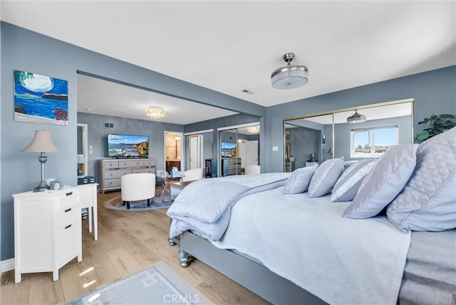 bedroom featuring light wood-style floors, two closets, and visible vents