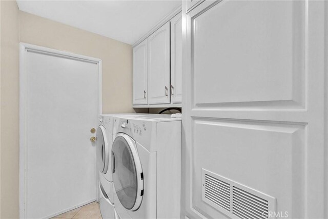 laundry area featuring visible vents, cabinet space, light tile patterned floors, and washing machine and clothes dryer