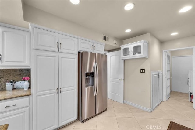 kitchen featuring visible vents, glass insert cabinets, stainless steel fridge, white cabinetry, and light tile patterned floors
