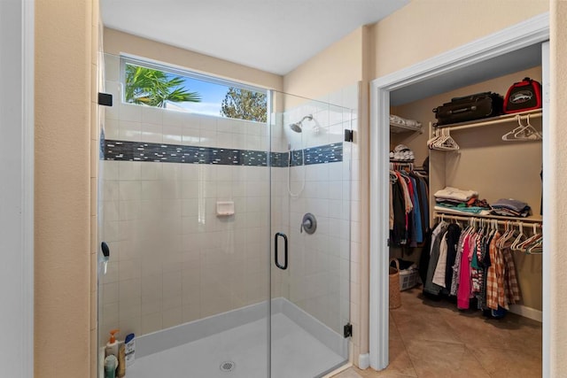bathroom with a shower stall, tile patterned floors, and a spacious closet