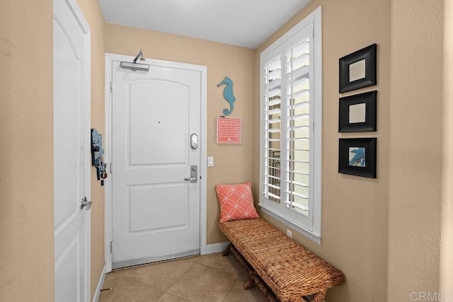 doorway to outside featuring tile patterned flooring, a healthy amount of sunlight, and baseboards