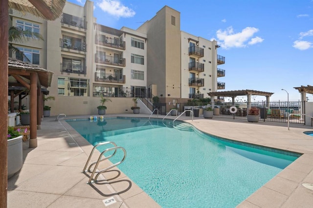 pool with fence, a pergola, and a patio