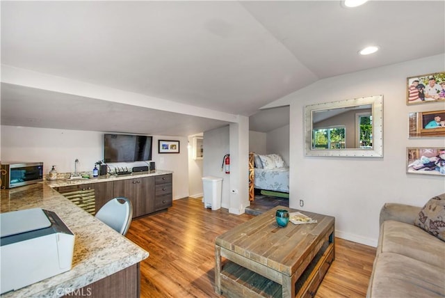 living room with baseboards, lofted ceiling, light wood-style floors, and recessed lighting