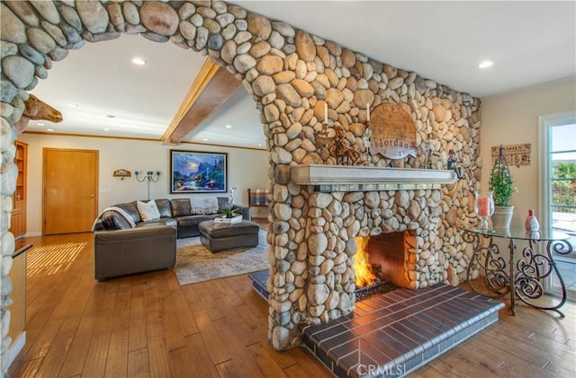 living room featuring a stone fireplace, ornamental molding, recessed lighting, and hardwood / wood-style flooring
