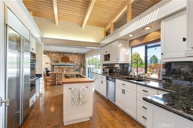 kitchen featuring white cabinetry, stainless steel appliances, a center island, decorative backsplash, and a sink