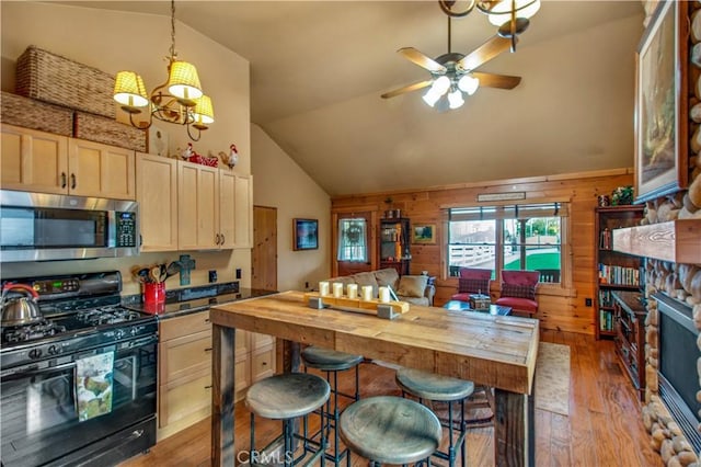 kitchen with black range with gas stovetop, wood-type flooring, lofted ceiling, and stainless steel microwave