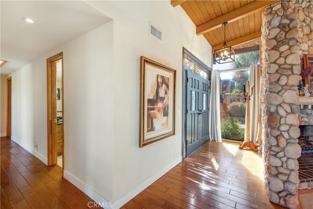 foyer entrance with wood ceiling, visible vents, baseboards, beamed ceiling, and hardwood / wood-style floors