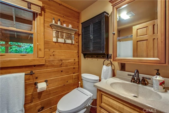 bathroom with vanity, toilet, and wooden walls