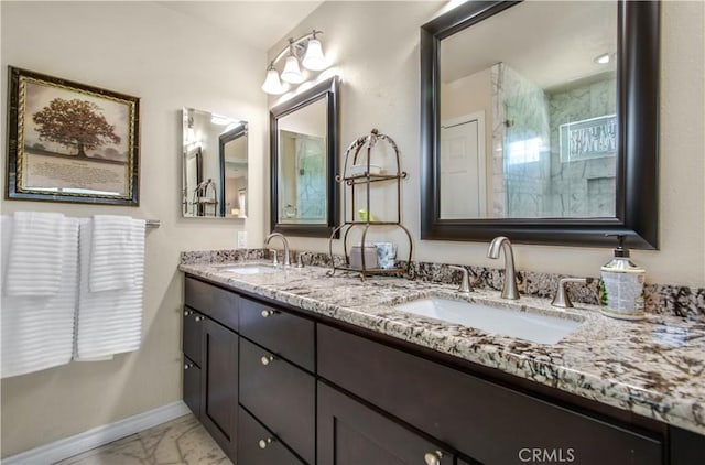 full bathroom with marble finish floor, a sink, double vanity, and baseboards