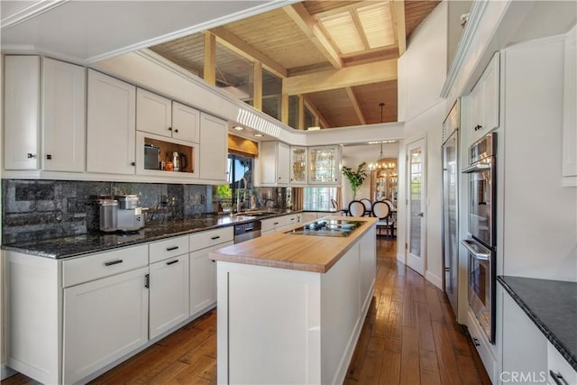 kitchen with stainless steel appliances, butcher block counters, a kitchen island, dark wood-type flooring, and backsplash