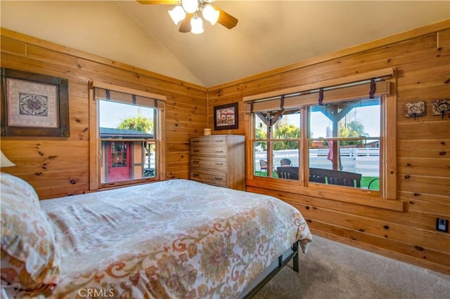 bedroom featuring lofted ceiling, wooden walls, and carpet floors