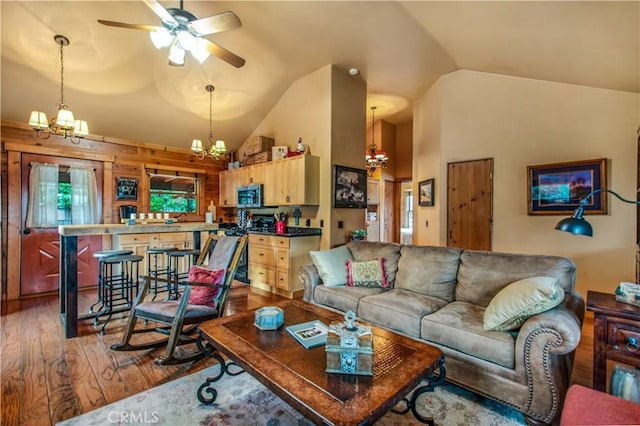 living area with ceiling fan with notable chandelier, high vaulted ceiling, and hardwood / wood-style flooring