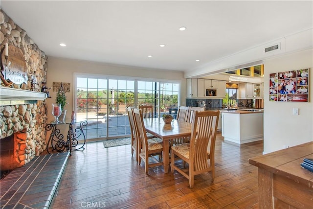 dining space with hardwood / wood-style floors, recessed lighting, a fireplace, and visible vents