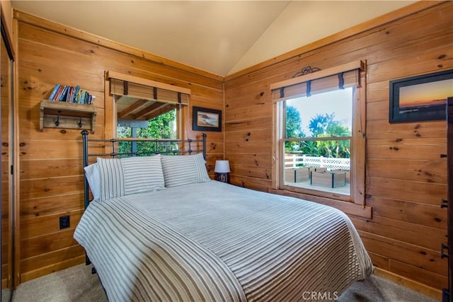 carpeted bedroom with multiple windows, lofted ceiling, and wood walls