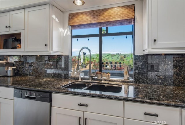 kitchen featuring decorative backsplash, white cabinets, dishwasher, dark stone counters, and a sink