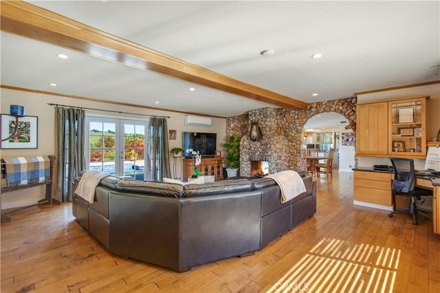living area with a wall unit AC, crown molding, arched walkways, beamed ceiling, and light wood finished floors