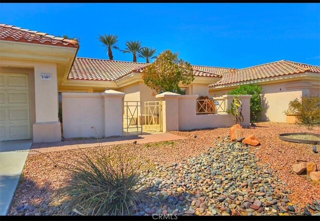 view of front of home featuring stucco siding, a gate, fence, a garage, and a tiled roof