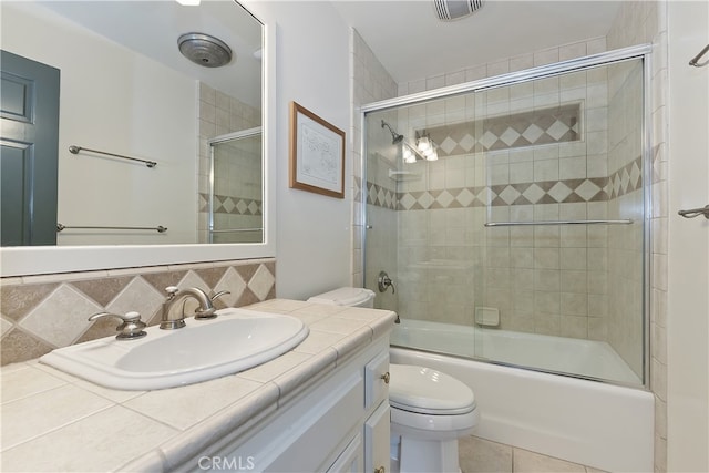 full bathroom featuring tasteful backsplash, visible vents, toilet, combined bath / shower with glass door, and vanity