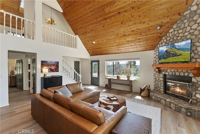 living room with stairway, wood finished floors, a stone fireplace, vaulted ceiling, and wooden ceiling