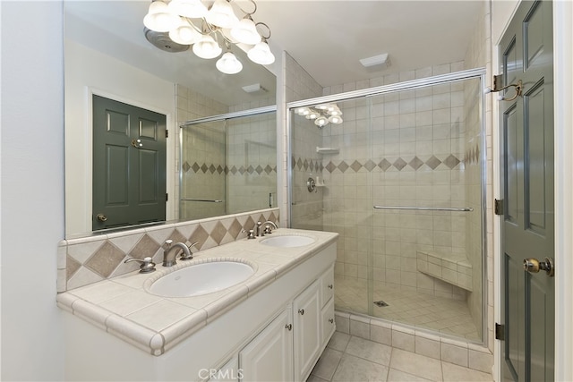 bathroom featuring a sink, a notable chandelier, a stall shower, and tile patterned flooring