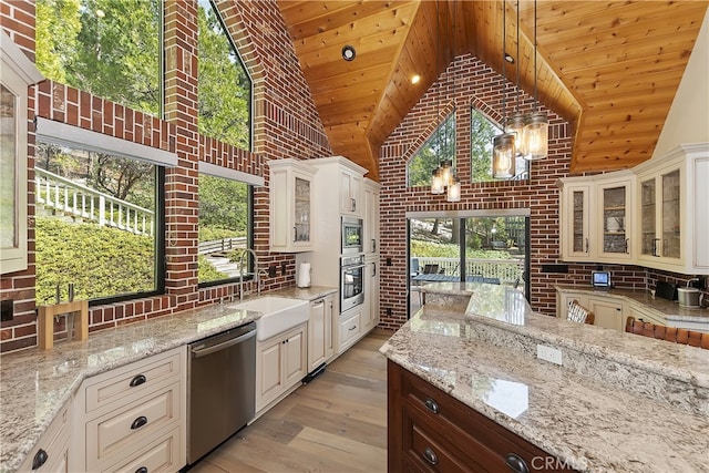 kitchen featuring backsplash, light stone counters, light wood-style flooring, stainless steel appliances, and a sink