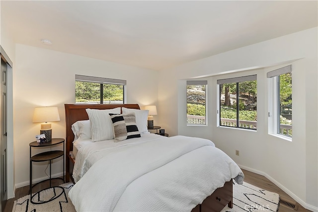 bedroom with visible vents, baseboards, and wood finished floors