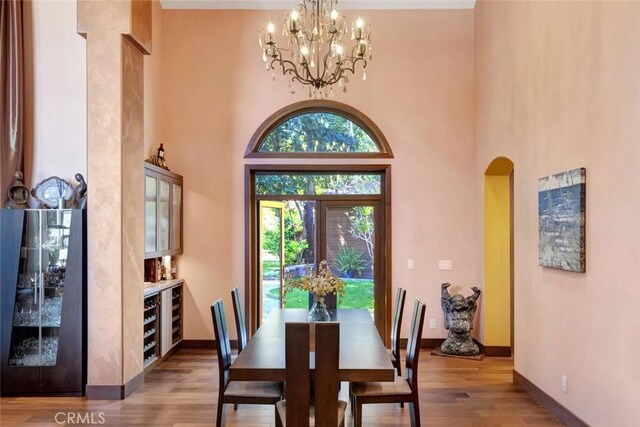 24925 Vista Verenda, Woodland Hills, CA 91367 - dining room with arched walkways, wood finished floors, a chandelier, baseboards, and a towering ceiling