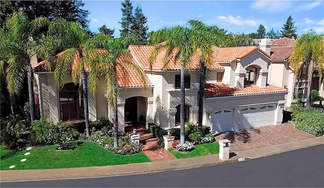 mediterranean / spanish-style house featuring an attached garage, a tiled roof, driveway, and stucco siding