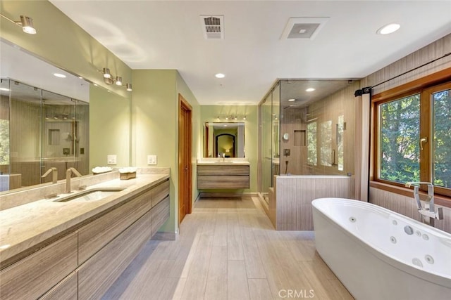 24925 Vista Verenda, Woodland Hills, CA 91367 - bathroom featuring two vanities, a shower stall, wood finished floors, a jetted tub, and recessed lighting