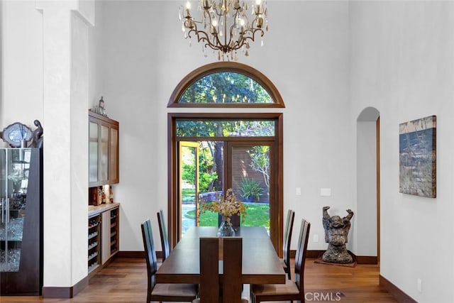 24925 Vista Verenda, Woodland Hills, CA 91367 - dining space with wood finished floors, a chandelier, a high ceiling, arched walkways, and baseboards