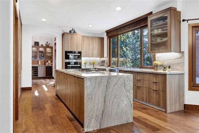 24925 Vista Verenda, Woodland Hills, CA 91367 - kitchen with modern cabinets, light wood-style floors, a kitchen island, light stone countertops, and recessed lighting
