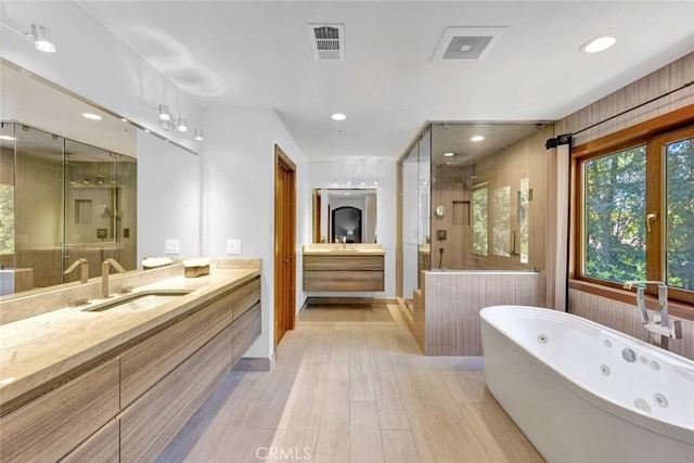 24925 Vista Verenda, Woodland Hills, CA 91367 - bathroom featuring a shower stall, two vanities, wood finished floors, a jetted tub, and recessed lighting